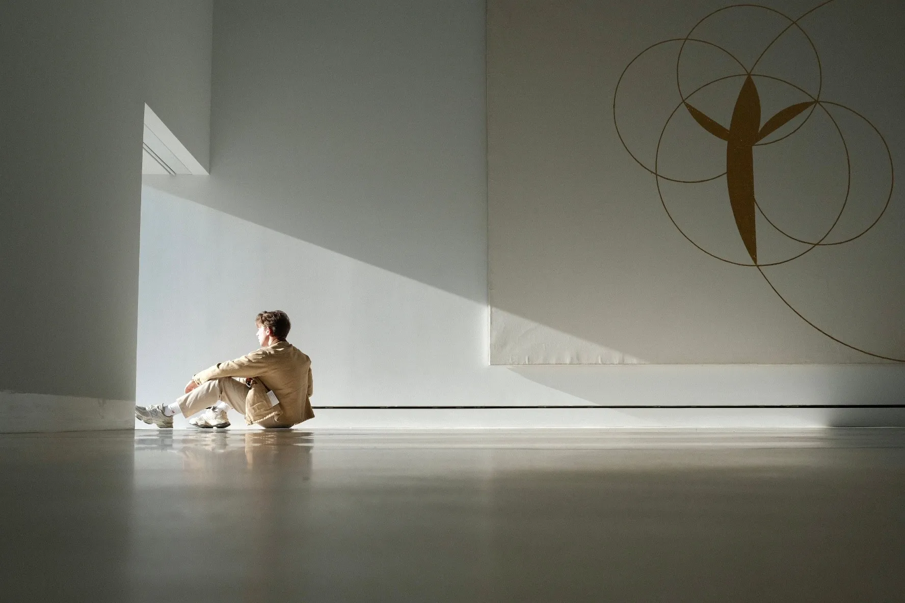 Sitting on a gallery floor in a diagonal of afternoon light