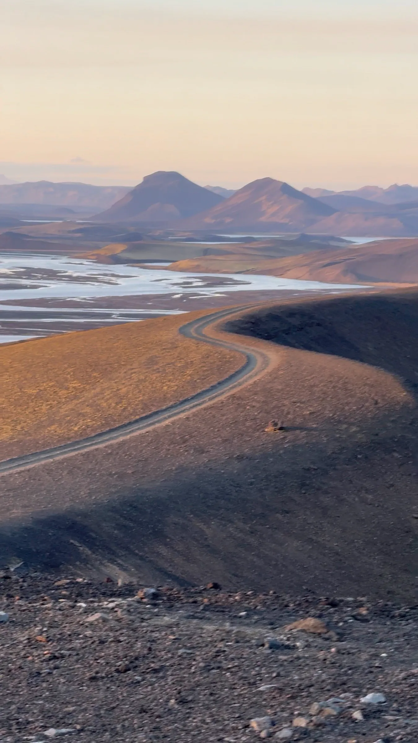 A gravel road winding through the highlands at golden hour